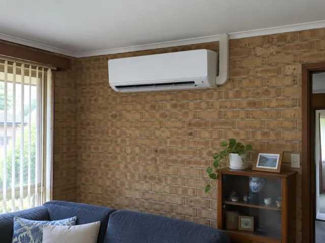Wall-mounted split system on a brick living room wall above a sofa in Modbury Heights